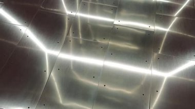 Parlak metalik plakalar parlak beyaz ışıkları yansıtıyor.