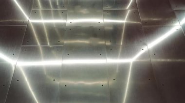 Yansıyan ışıklarla parlak metalik bir zeminde yürüyen ayaklar