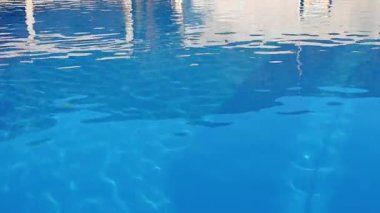 Sakin havuz suyu yüzeyi, hafif dalgalanmaları olan bir binayı yansıtıyor. Biraz sükunet katıyor.