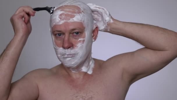男は剃刀で頭を剃る 接近中だ 白い背景 はげ頭 動画クリップ