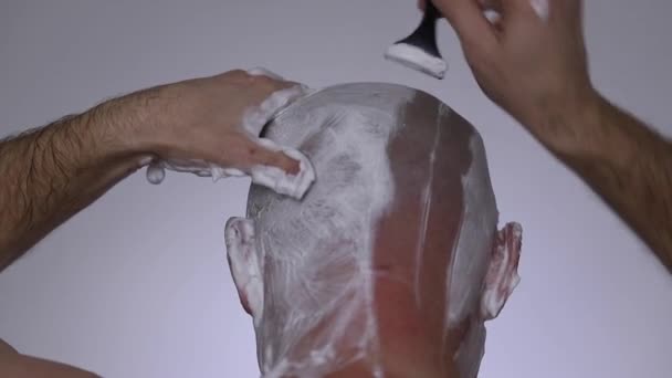 男は剃刀で頭を剃る 彼の頭の後ろ バックビュー ロイヤリティフリーのストック動画