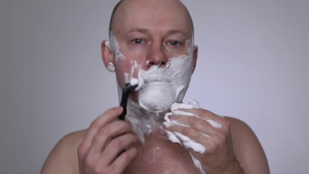 剃刀で男が髭を剃る 接近中だ 白い背景 はげ頭 ロイヤリティフリーストック映像