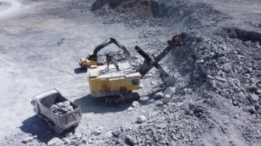 Taş ocağı kazıcısı kayaları bir kamyona yüklüyor..