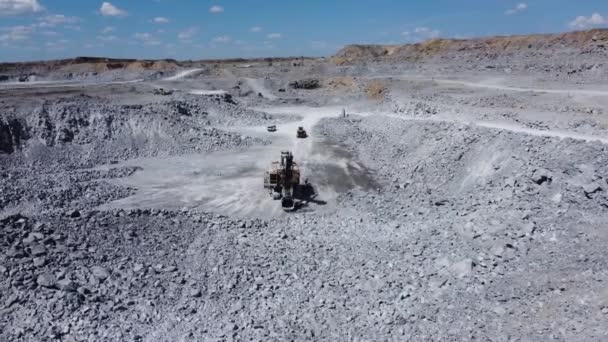 大規模な採掘掘削機が採石場に立っている ドライバは掘削機から離れて移動している カメラは掘削機の周りを飛んで 長いショット 動画クリップ