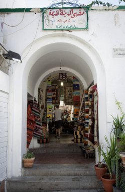 Trablus, Libya, 4 Kasım 2009. Eski şehir Medine pazarındaki bir goblen dükkanının kemerli girişi. Bir turist indirimdeki halılara bakıyor..