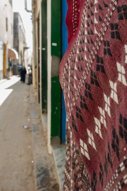 Trablus, Libya, 4 Kasım 2009. Libya 'nın Trablus şehrinde sakin bir cadde, duvarın kenarında bir halı ve arka planda yayalar asılı..