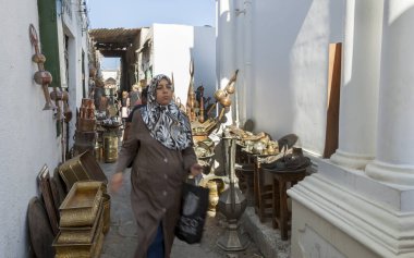Trablus, 4 Kasım 2009. Pirinç ve metal işçileri ve antika satıcıları ürünlerini Trablus 'un eski şehir bölgesi olan Medina, Ghadema' da satıyorlar. Alışveriş çantalı bir kadın geçiyor..
