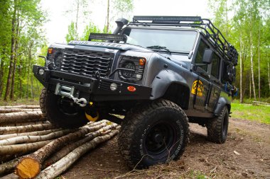 Equipped Land Rover Defender in the forest, ready for off road, shows his abilities clipart