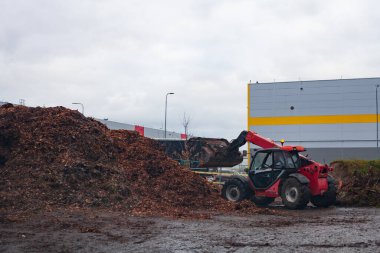 Tractor is working at the city green waste dump clipart