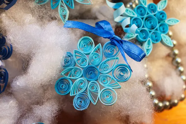 Kağıtlar, tüy dökme tekniğiyle yapılan kar taneleri yaylar ve boncuklarla çevrili.