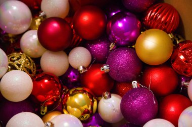 Noel ağacını süslemek için kırmızı, altın ve pembe tonlarda renkli Noel ağacı süslemeleri..