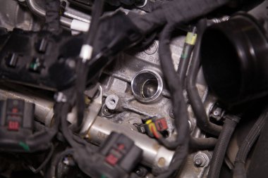 Motor kapağı çıkarılmış, bujiler çıkarılmış ve kablolar açığa çıkmış bir arabanın kısmen parçalanmış motor bölmesi.