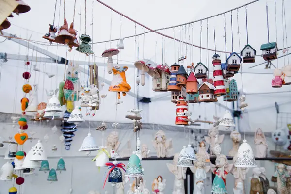Tasarımcı kil, deniz feneri, çan, ev ve melekler şeklinde süslemeler ve hediyelik eşyalar asıyor, el yapımı, şehir panayırındaki bir pazarda sergileniyor.