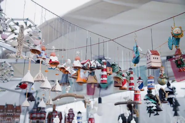 Tasarımcı kil, deniz feneri, çan, ev ve melekler şeklinde süslemeler ve hediyelik eşyalar asıyor, el yapımı, şehir panayırındaki bir pazarda sergileniyor.