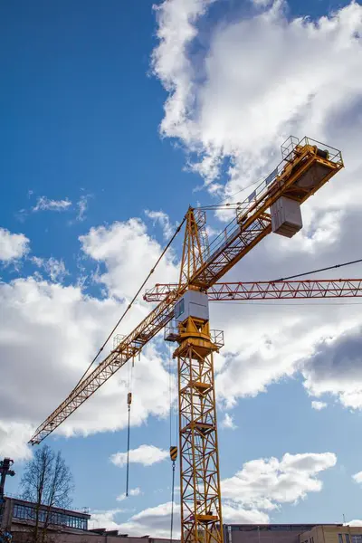 Eski bir binanın yıkım alanında mavi gökyüzüne karşı inşa edilmiş sarı bir vinç.