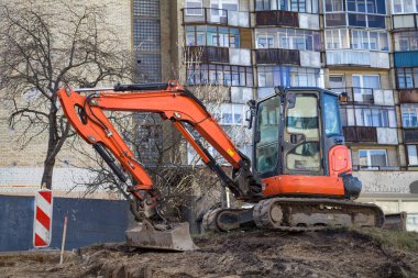 Eski binaların arasında bir inşaat alanında temel kazan bir buldozer.