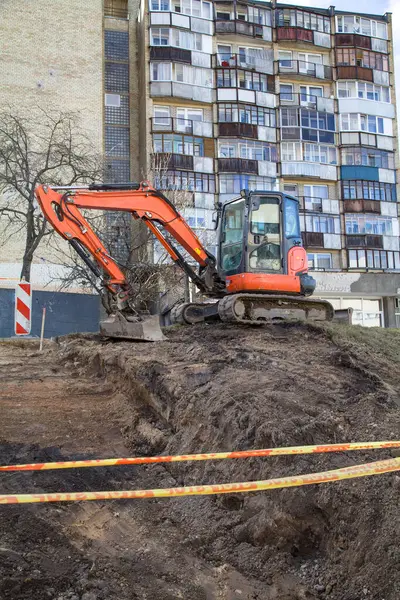 Eski binaların arasında bir inşaat alanında temel kazan bir buldozer.