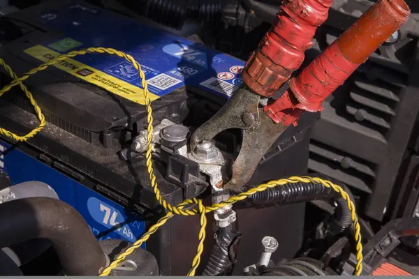 Pozitif pil terminaline bağlı iri kırmızı bir jumper kablo kıskacı, açık kaputun altında açıkça görülüyor.