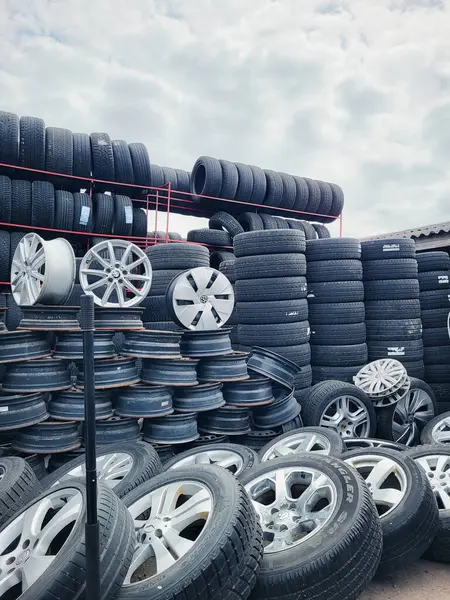 Vilnius, Litvanya - 08-05-2025 - kullanılmış lastik, eski alaşımlı tekerlekler duvarı, ve bir otomobil yedek parça pazarında lastik yığını