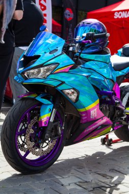 Vilnius, Litvanya - 31-05-2025 - Bir araba fuarında gidonunda miğfer olan parlak, parlak masmavi ve pembe güneş gözlüklü özel plastikten yapılmış bir motosiklet