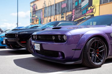 Vilnius, Litvanya - 31-05-2025 - Güneşli bir günde, şehir tarzı otomotiv sahnesinde grafiti kaplı bir duvarın yanına park edilmiş iki Dodge Challenger kaslı arabası