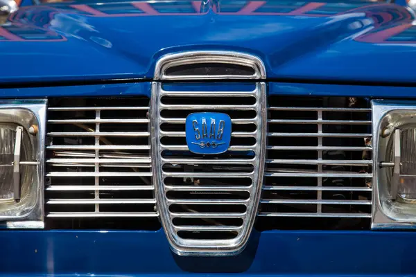 Vilnius, Litvanya - 31-05-2025 - Mavi klasik Saab 96 'nın radyatör ızgarasındaki sembolik Saab amblemine yakın plan, doğal ışık altında retro araba detayı