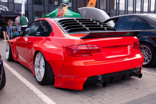 Вильнюс, Литва - 31-05-2025 - Rear view of red BMW 3 Series with looking custom body kit, agressive negative camber, and chrome deep-lip wheels