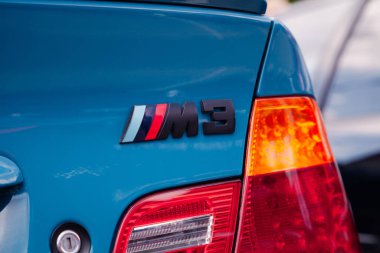 Vilnius, Litvanya - 31-05-2025 - Siyah BMW M3 amblemi canlı mavi bir spor sedan kapağının üzerinde