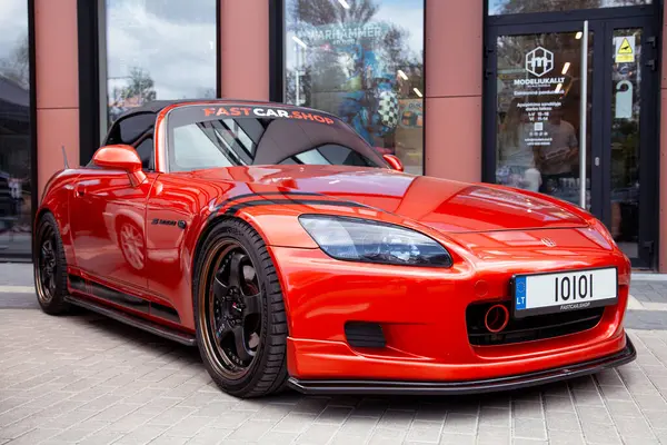 Vilnius, Litvanya - 31-05-2025 - Sportif kırmızı Honda S2000 yüz gerdirme modeli agresif ön tampon, özel tekerlekler ve kentsel bir ortamda park edilmiş duran düşük duruş
