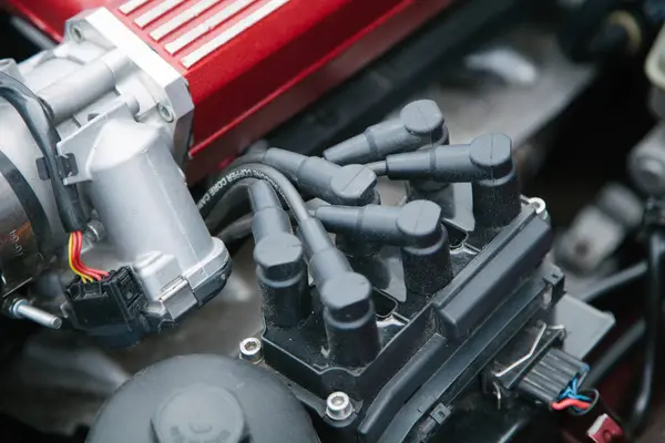 Görünür kablo takımı, elektrik konnektörleri ve metalik kırmızı kapaklı emme manifoldunun bir kısmı kaputun altında performans odaklı bir kurulum olduğunu gösteriyor.