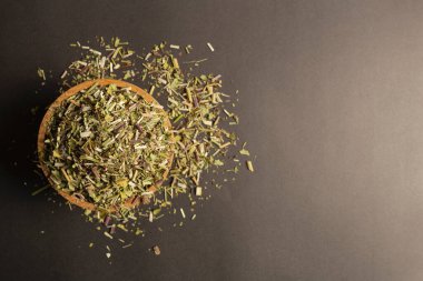 Catnip herb in latin - Nepeta cataria in a wooden bowl on a black background. Medicinal herb.  Flat lay, top view, copy space