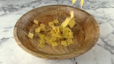 Tahta tabağa düşen çiğ quadretti makarnası. yavaş çekim.