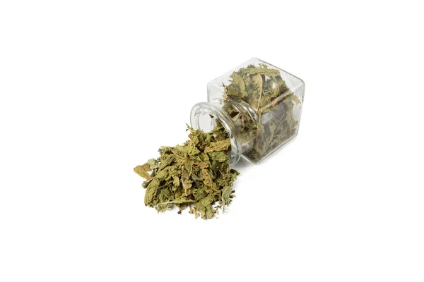 Dried leaves o Lemon verbena in latin Aloysia citrodora falling out of a glass jar isolated on white background. Medicinal herb. Lemon verbena leaf extract is used for its energizing and refreshing properties, lemony scent.