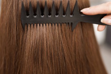 Saç bakımı. Keratin tedavisi. Güzellik modası. Profesyonel kozmetik. Esmer, güzel bir kadın, sağlıklı saçlarını tarıyor. Uzun kahverengi saçlarını tarayan kadın portresi