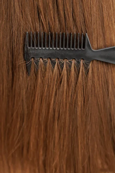 Saçlarını tarayan bir kız. Bornozlu neşeli genç Asyalı bayan yatak odasında oturuyor, güzel ipek saçlarını fırçayla tarıyor. Saç bakım ürünleri kavramı