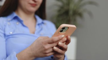 Sosyal medyayı kontrol eden mutlu bir genç kız akıllı telefonu evde tutuyor. Gülümseyen genç bir kadın cep telefonu uygulaması kullanıyor oyun oynuyor, internetten alışveriş yapıyor, sipariş veriyor kanepeye rahatça servis yapıyor..