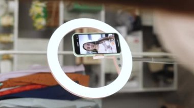 Çevrimiçi çalışan genç kadın nüfuzcunun dikey videosu sosyal medya için içerik yaratıyor, telefon tripod makyaj sanatçısıyla halka ışığının arkasından çekiliyor, kızlar için bahşiş ile video kaydediyor.