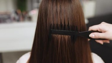 Saç bakımı. Keratin tedavisi. Güzellik modası. Profesyonel kozmetik. Esmer, güzel bir kadın, sağlıklı saçlarını tarıyor. Uzun kahverengi saçlarını tarayan kadın portresi