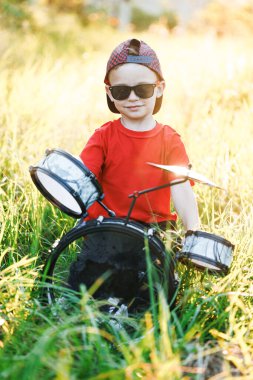Mutlu Kafkas Çocuk Oyuncak Davulunu Yeniyor. Küçük komik çocuk davul çalıyor. Oyuncak Davulda Çubuklarla Vuruşan Adam. Çubuklu neşeli çocuk. Çocuk Eğitimi Konsepti