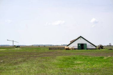 HORTOBAGY, HUNGARY 23 NİSAN 2022 Uçsuz bucaksız, kahverengi ve yeşil çimlerin altında, çoğunlukla bulutlu bir gökyüzünün altında sazdan yapılmış çatısı olan küçük bir beyaz yıkamalı bina. Binanın tek bir tane var.