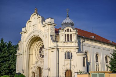 HODMEZOVASARHELY, HUNGARY MAYIS 06, 2022 Görkemli krem renkli bir kilise berrak mavi gökyüzüne karşı dimdik ayakta duruyor, parlak güneş ışığıyla vurgulanan karmaşık mimari ayrıntıları. Kilisenin.