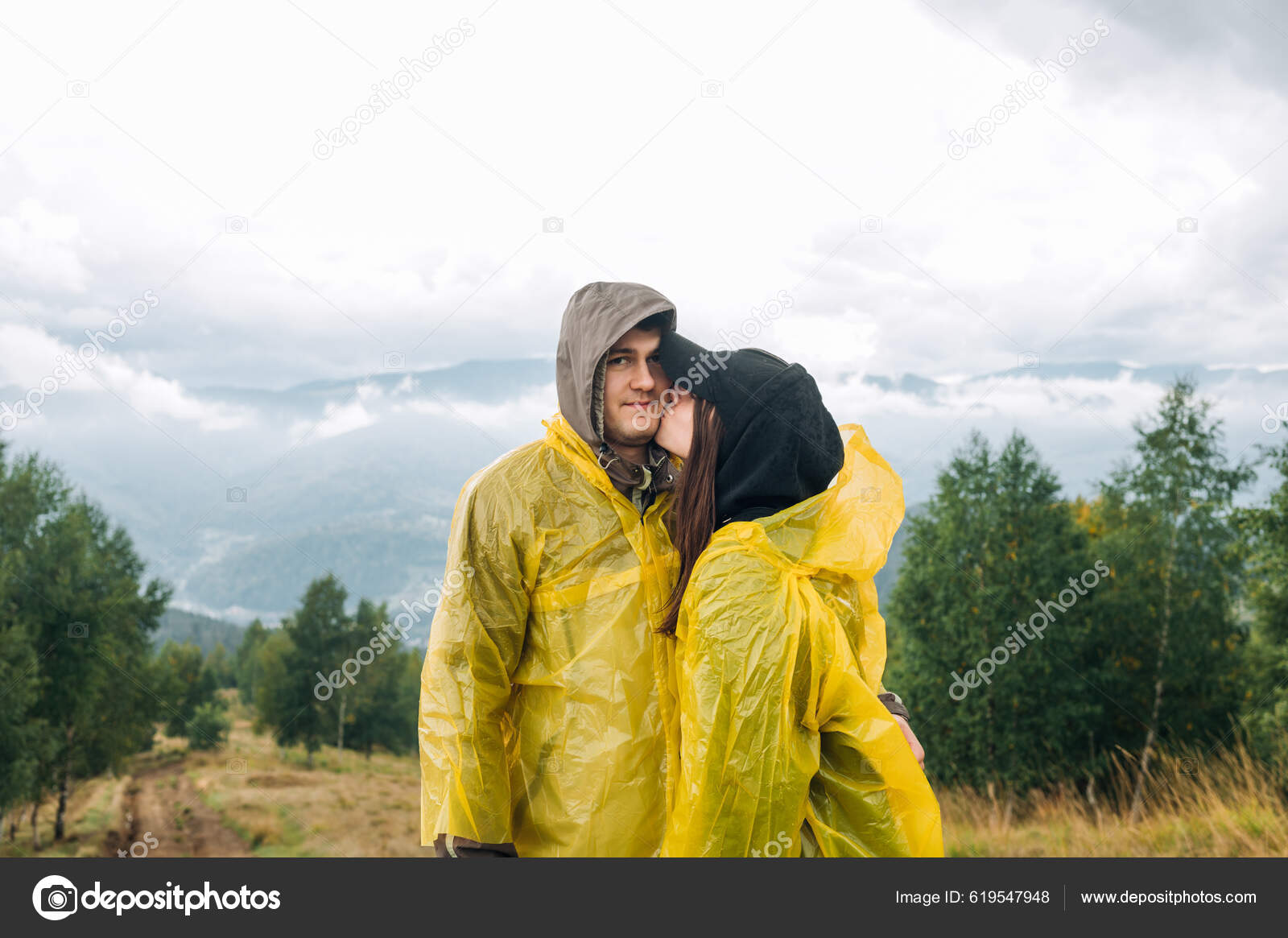 Cute Couple Raincoats Standing Mountains Rain Background Cloudy