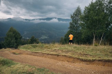 Genç bir adam, güzel doğal manzaranın arka planına tırmanırken çalılara işiyor..