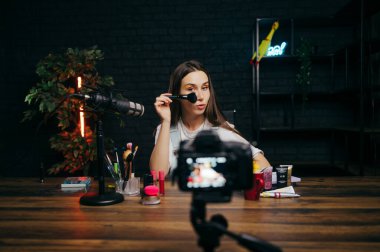 Güzellik blogcusu kadın kameraya makyöz sınıfını gösteriyor, eklemlerini kullanıyor ve kameraya bakıyor. Güzel fotoğraf..