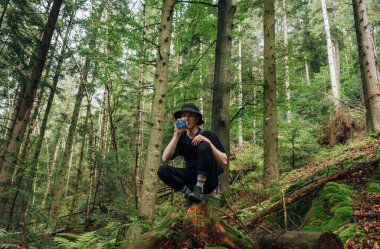 Panama 'da yürüyüş yapan komik genç bir turist dağlardaki ormanda oturur, su içer ve dinlenir..