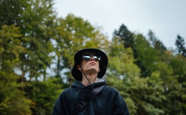 Panamalı bir erkek turistin yakın plan fotoğrafı ve ağaçların arka planında güneş gözlüğü..