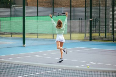 Komik bayan tenisçi tenis zaferinden dolayı eğleniyor. Elinde raketle kendi etrafında dönüyor..