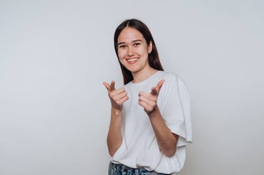 Genç bir kadın gülümsüyor ve basit bir stüdyo ortamında oyuncaklarla poz veriyor.