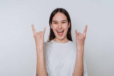 Genç Asyalı kadın arka planda gülümserken rock 'n roll hareketi yapıyor.