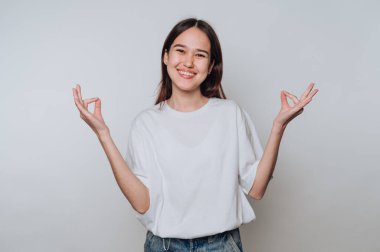 Genç Asyalı kadın gündüz vakti sakin bir kapalı ortamda farkındalık ve meditasyon yapıyor.